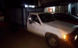 Camioneta Toyota tipo estaquitas, blanca con verde y redilas azules.